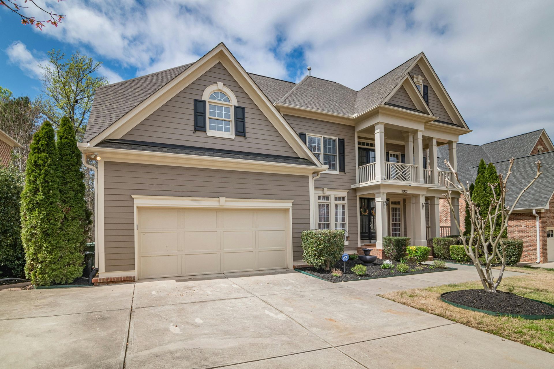 A stone retaining wall and built-in stone steps on a sloping, wood-chipped yard next to a house with gray siding.