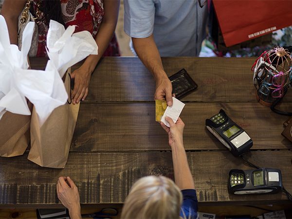 A woman is giving a credit card to a man at a counter.