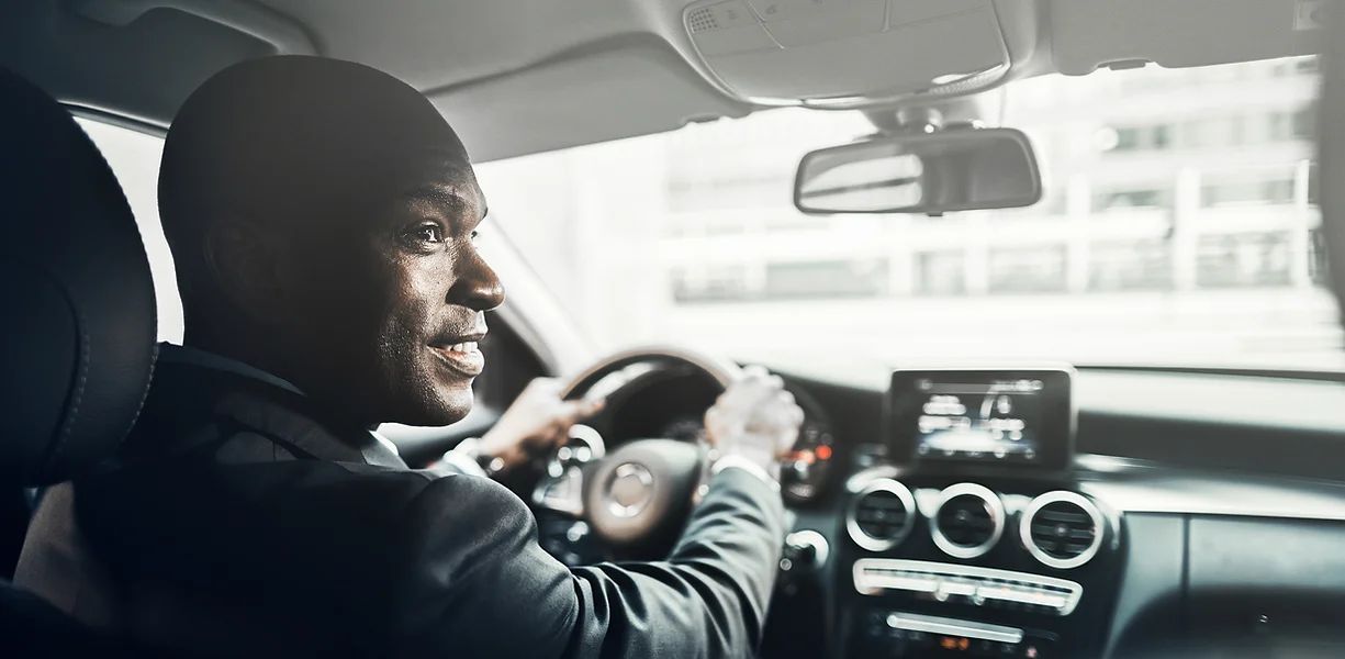 A man in a suit is driving a car.