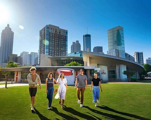 A group of people are walking in a park in front of a building.
