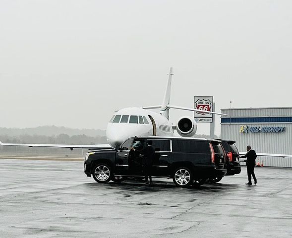 A black suv is parked in front of an airplane