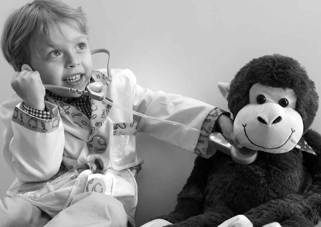 Child with stethoscope on stuffed monkey's chest.