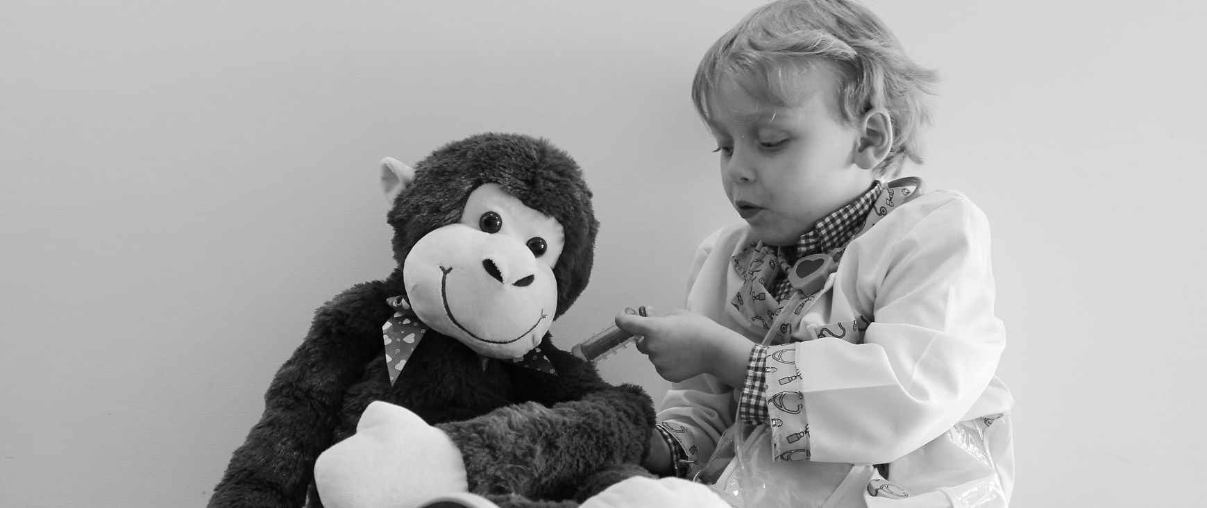 A little girl is playing with a stuffed monkey.