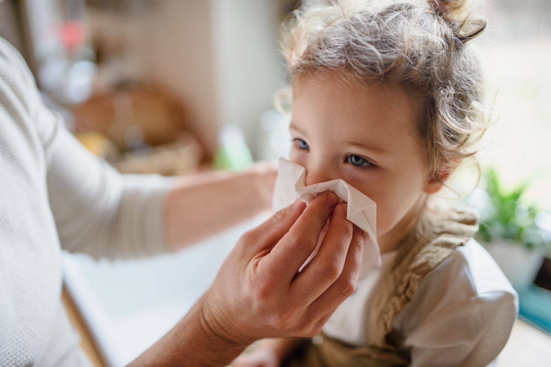 Parent holding a tissue over child's nose.