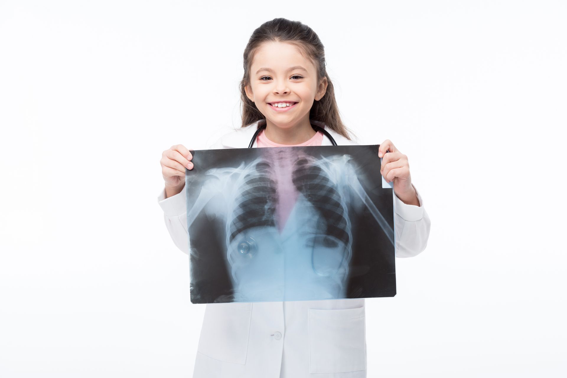 Young, smiling girl holding an x-ray in front of her.