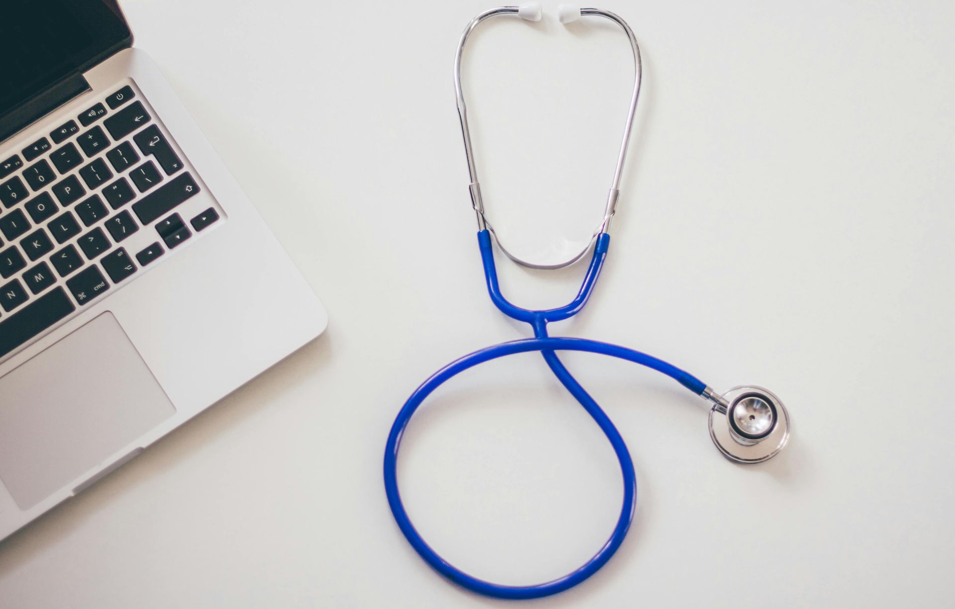 Stethoscope and computer on white table.