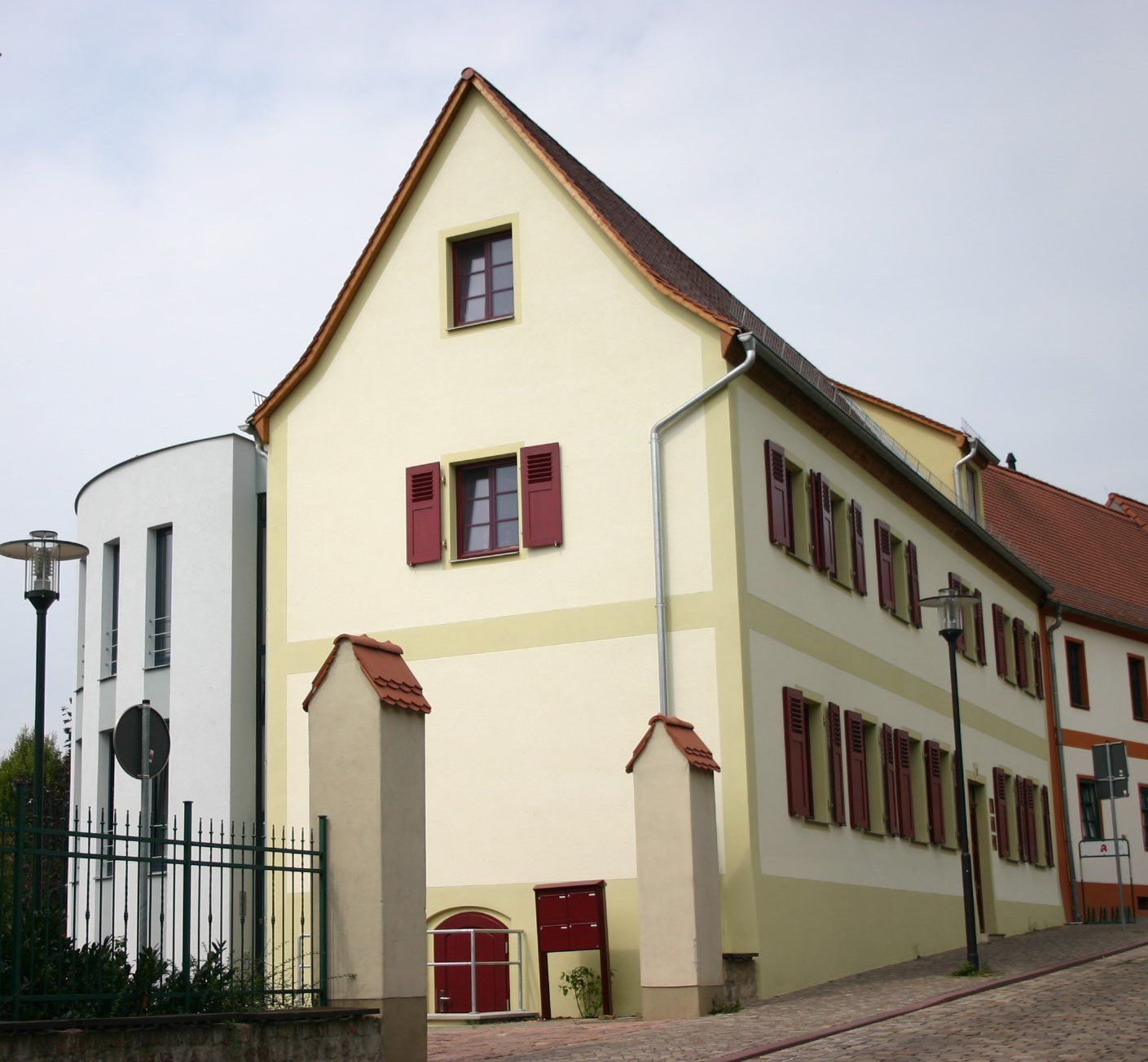 Eine Reihe cremefarbener Häuser mit roten Fensterläden und steilen Giebeldächern auf einer Kopfsteinpflasterstraße