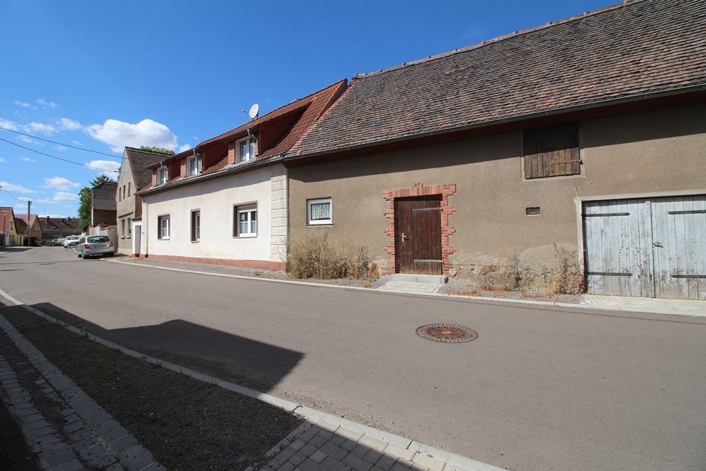 Ruhige Dorfstraße mit alten Stuckhäusern und Ziegeldächern unter blauem Himmel