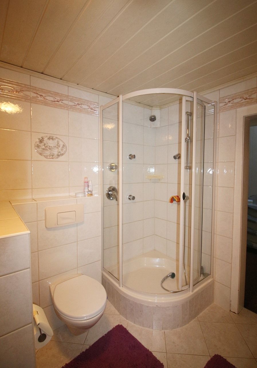 Kompaktes weißes Badezimmer mit WC und Eckduschkabine
