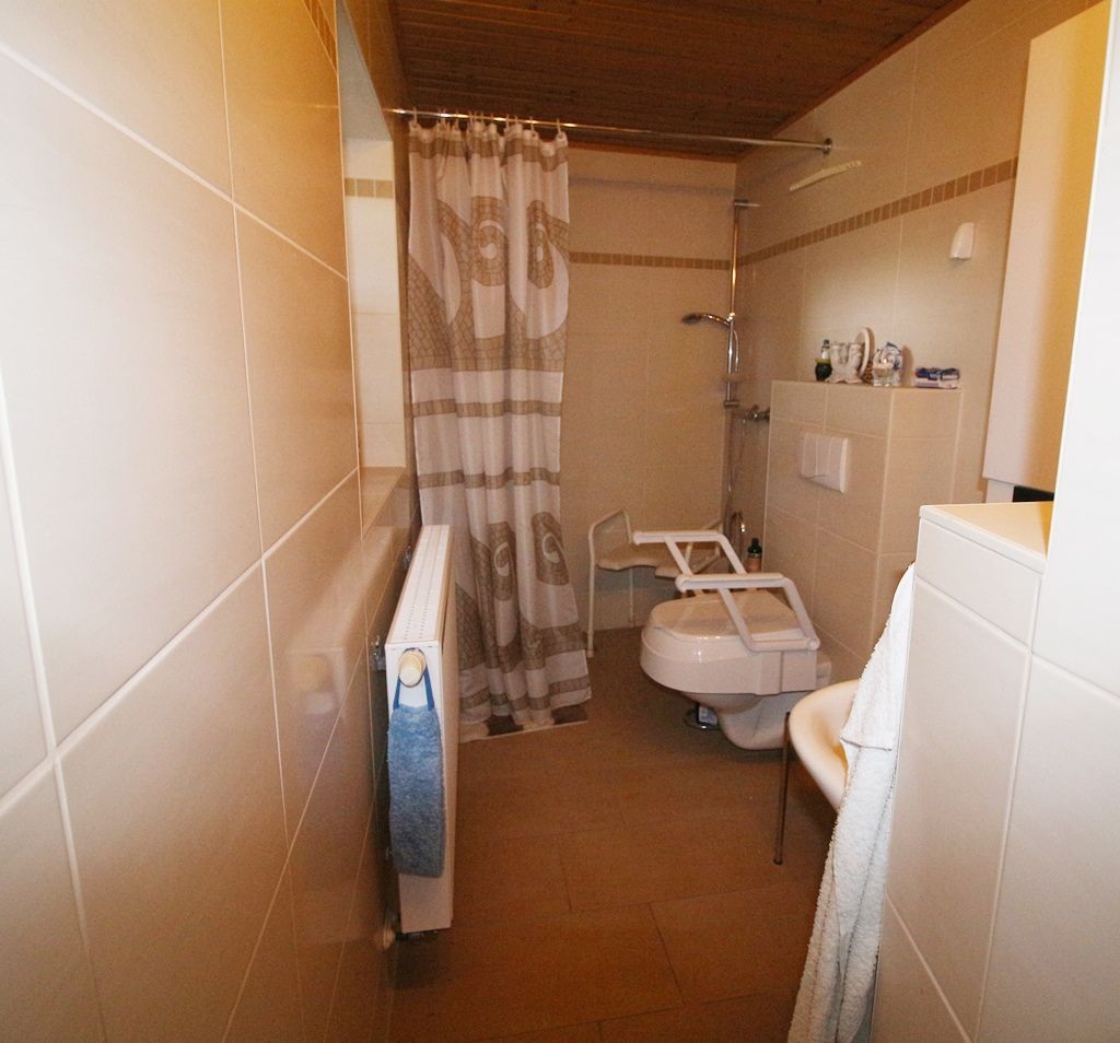 Kleines beigefarbenes Badezimmer mit Duschvorhang, Toilette, Waschbecken und Handtuchhalter.
