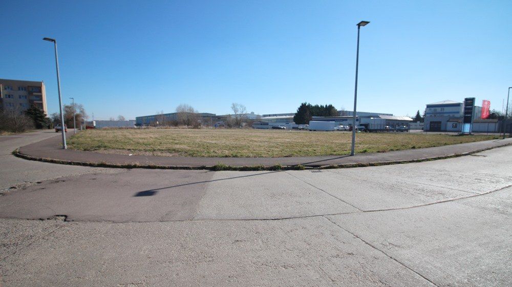 Leerer Kreisverkehr mit grasbewachsener Mitte, Straßenlaternen und klarem blauen Himmel