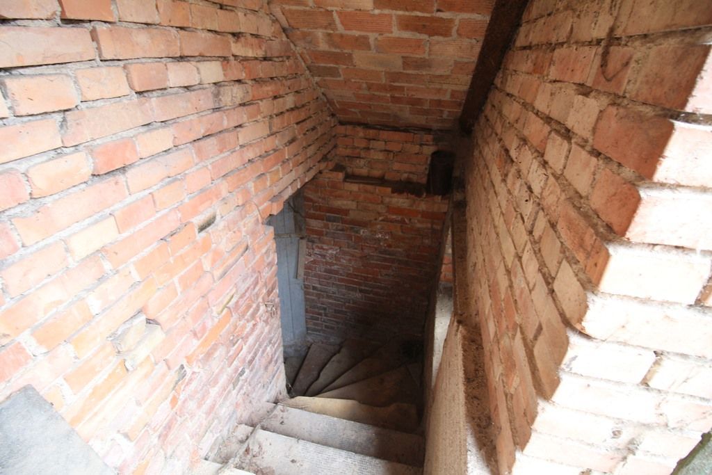 Schmale Backsteintreppe, die in einen dunklen Keller oder unterirdischen Gang hinabführt