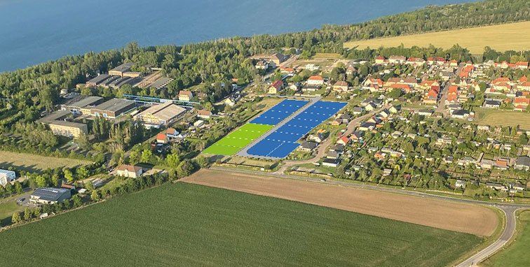 Luftaufnahme einer ländlichen Stadt mit blau gedeckten Gebäuden und grünen Feldern unter klarem Himmel
