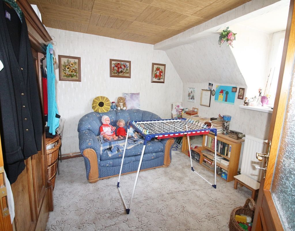 Kleines Wohnzimmer mit blauem Sofa, Wäscheständer, Holzschreibtisch, Wandbildern und hellem Fensterlicht