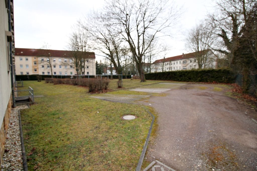 Wohnhausinnenhof mit Rasen, Kiesweg, kahlen Bäumen und Gebäuden im Hintergrund