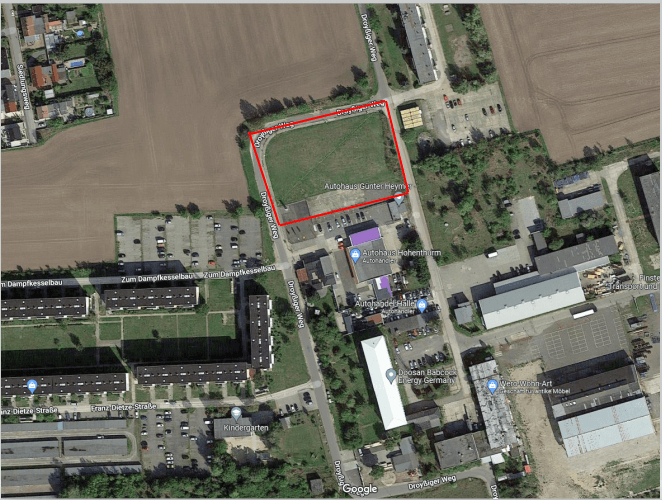 Luftaufnahme von Ackerland und Gebäuden, wobei ein rot umrandetes Feld im oberen Zentrum hervorgehoben ist.