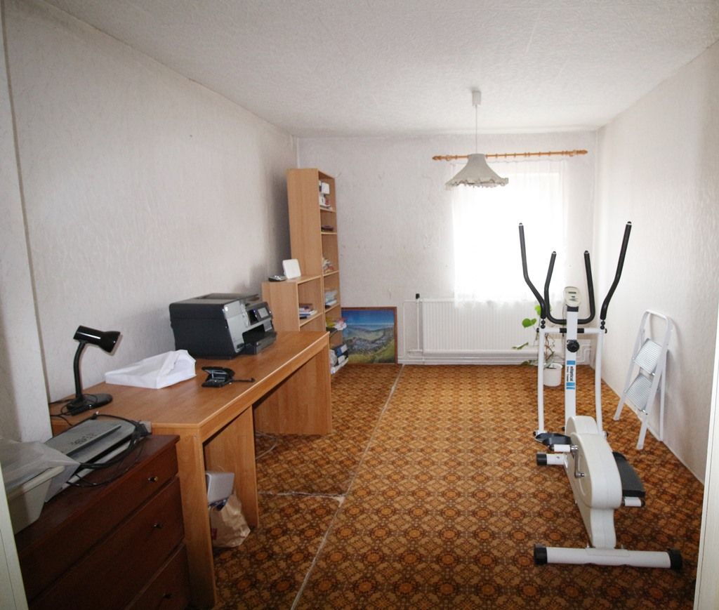 Heimbüro mit Schreibtisch, Computer und Heimtrainern in einem langen, schmalen Raum