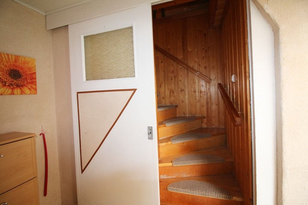 Treppe mit Holzstufen und Handlauf durch offene weiße Tür sichtbar.
