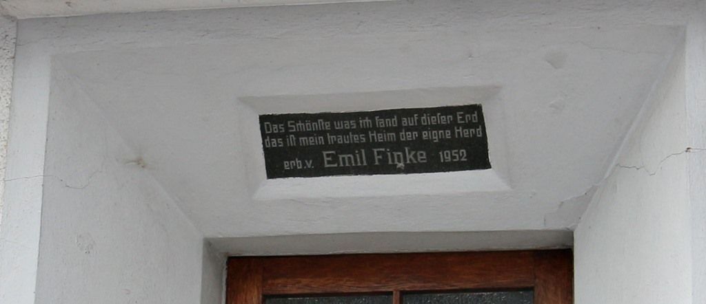 Schwarzes Wandschild über einer Tür in einem weiß getünchten Flur