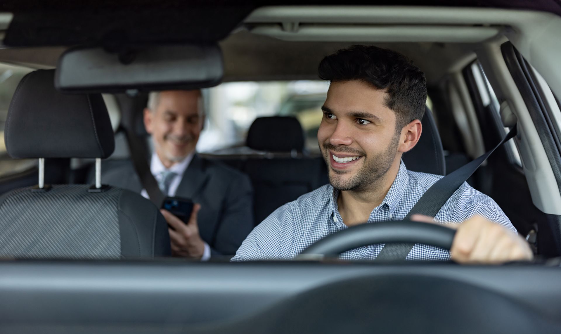 Un uomo sta guidando un'auto mentre un altro uomo è seduto sul sedile posteriore.