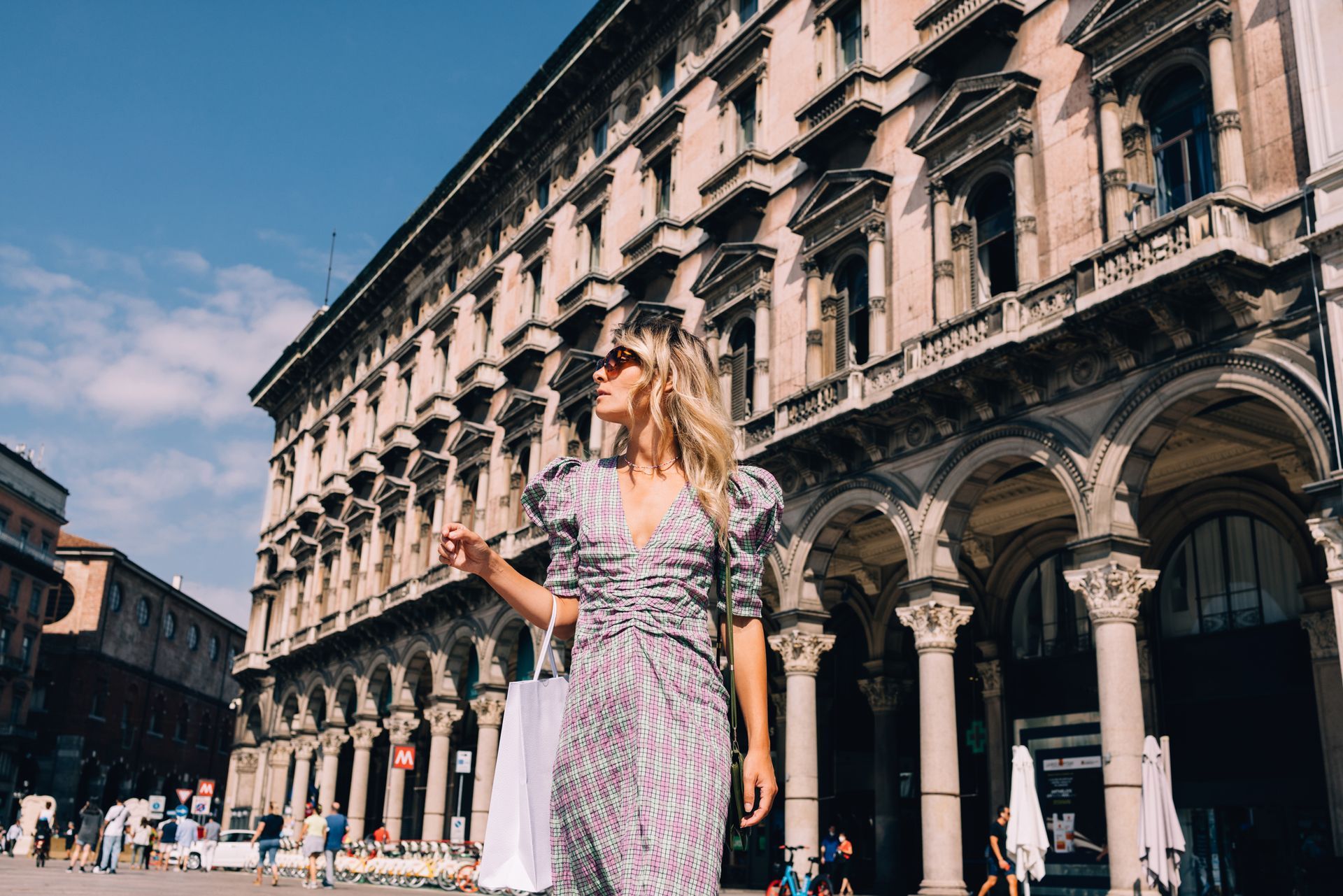 Una donna in abito lungo cammina davanti a un grande edificio.