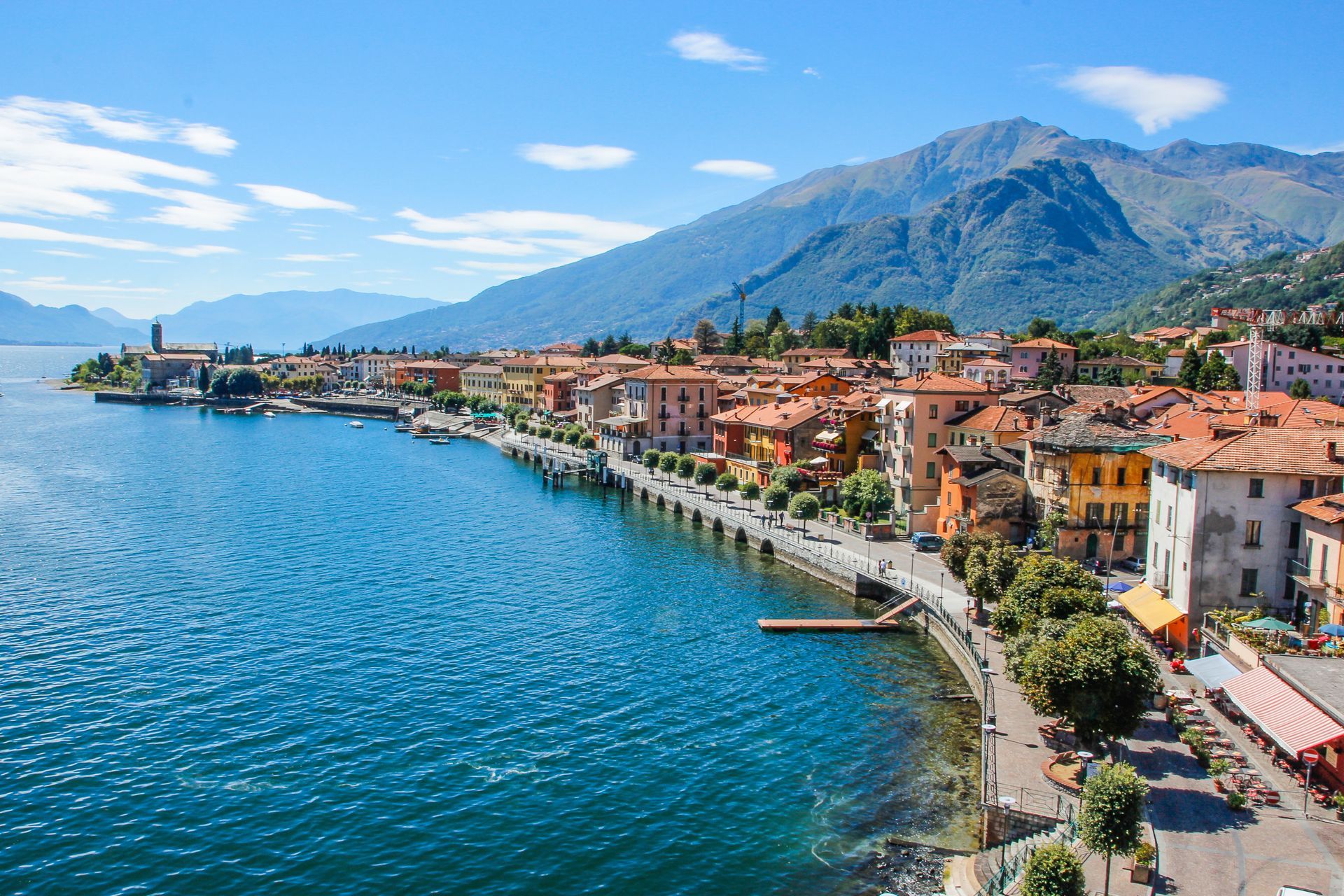 Una vista aerea di una piccola città sulla riva di un lago con le montagne sullo sfondo.