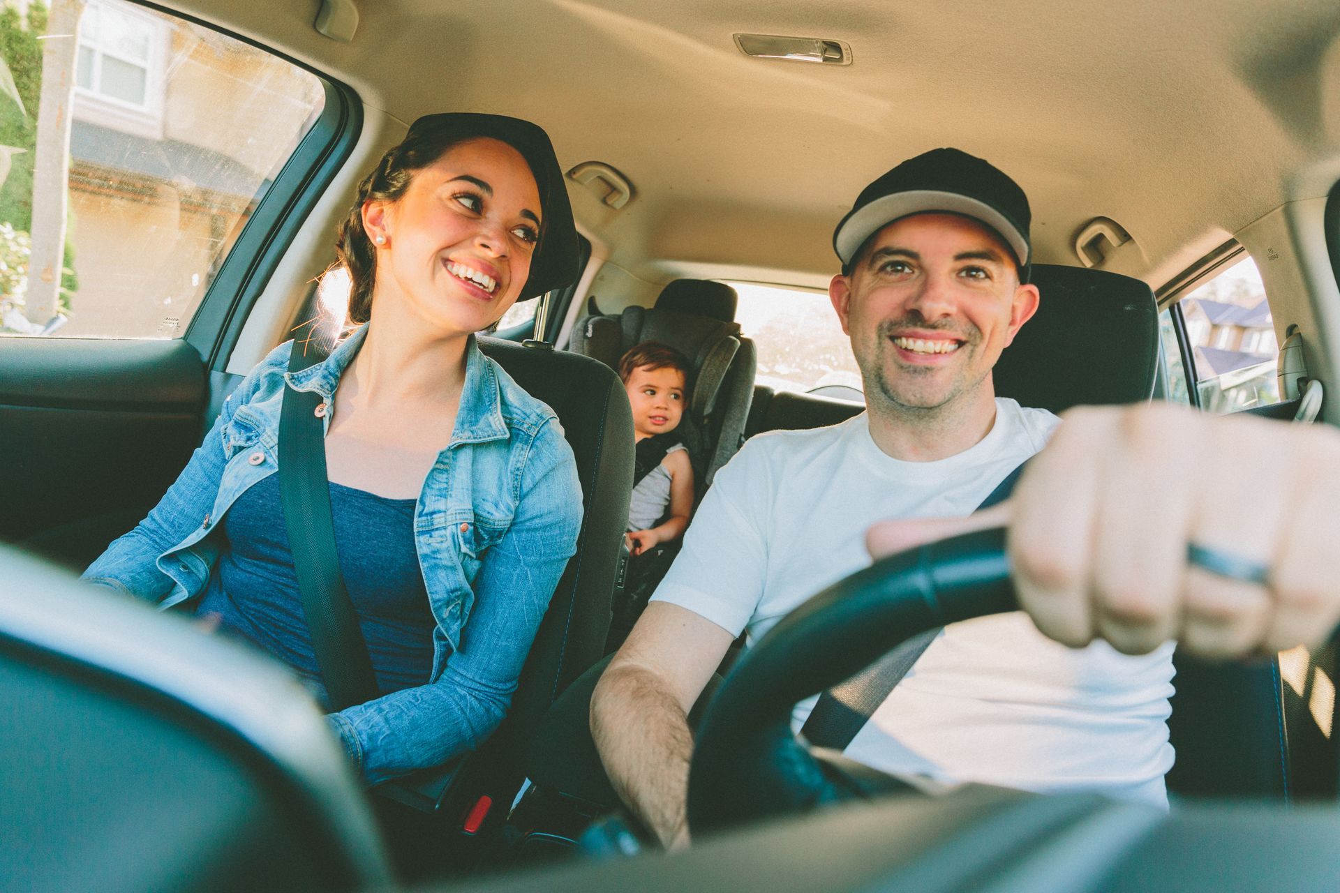 A man is driving a car with a woman and a child in the back seat.