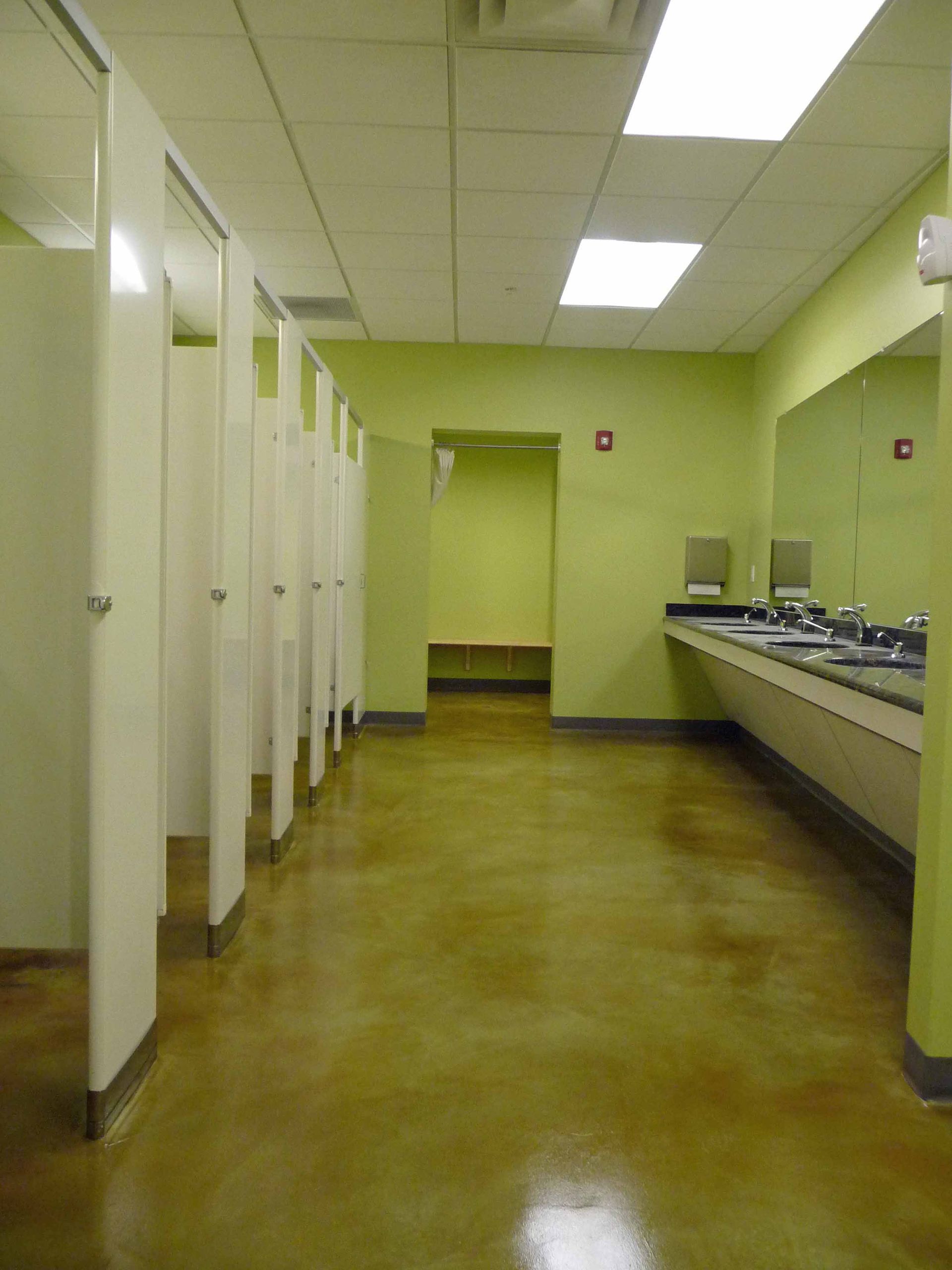 Empty public restroom with sinks, stalls, and pale green walls