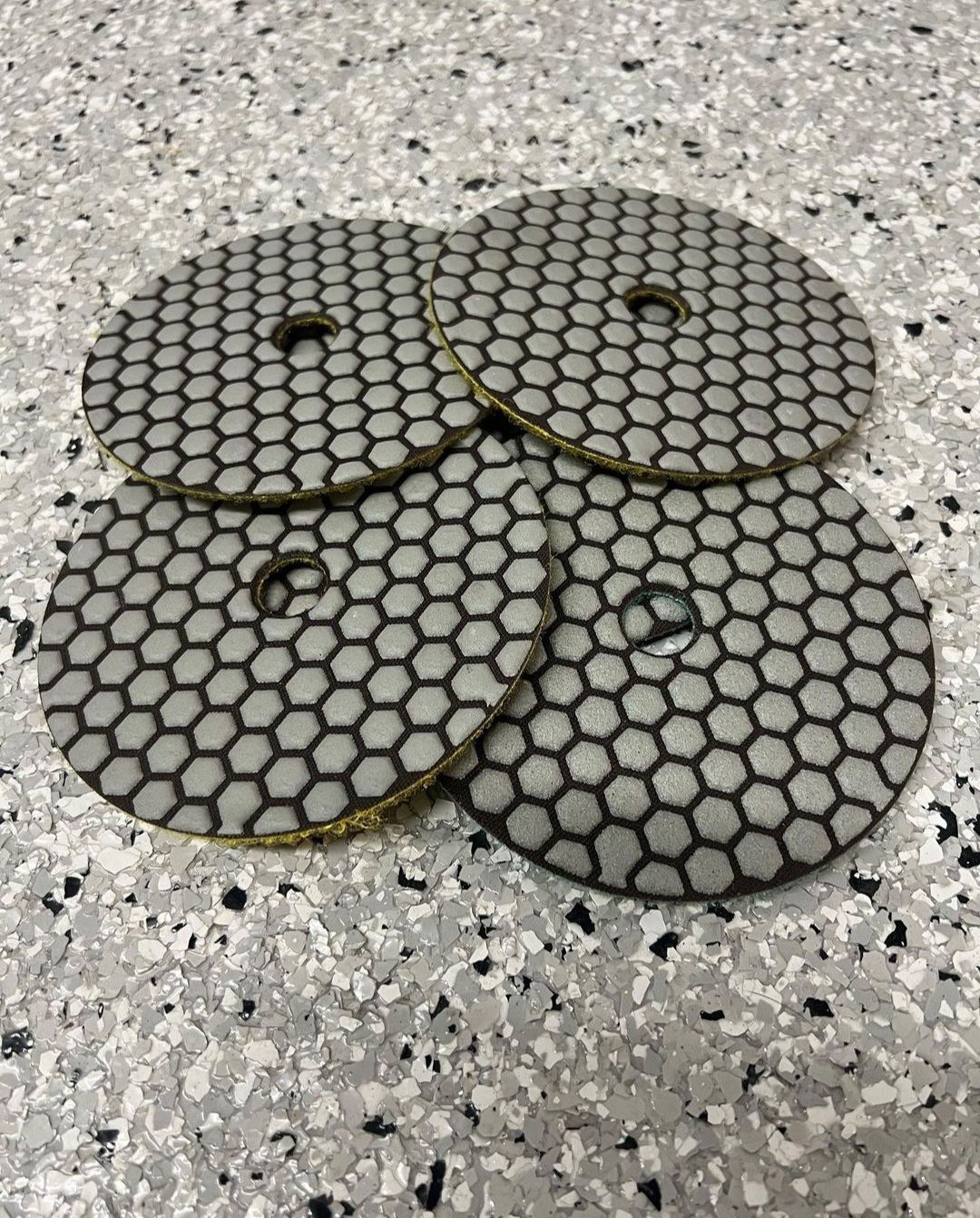 Four hex-patterned round tiles stacked on a speckled gray floor