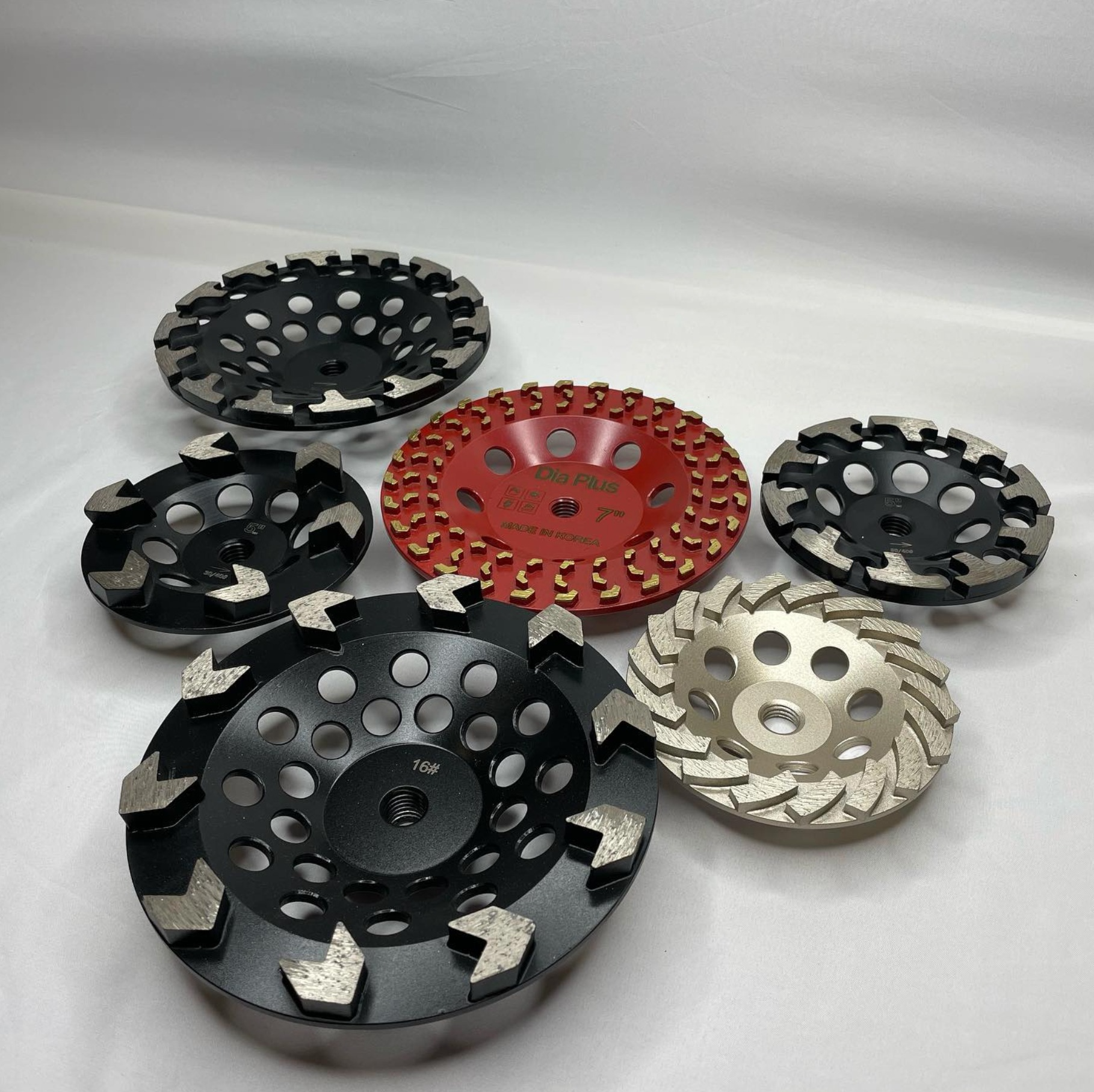 Five metal grinding wheels in black, red, and silver on a light background