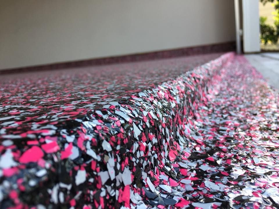 Close-up of a speckled black, pink, and white patterned carpeted step in a hallway