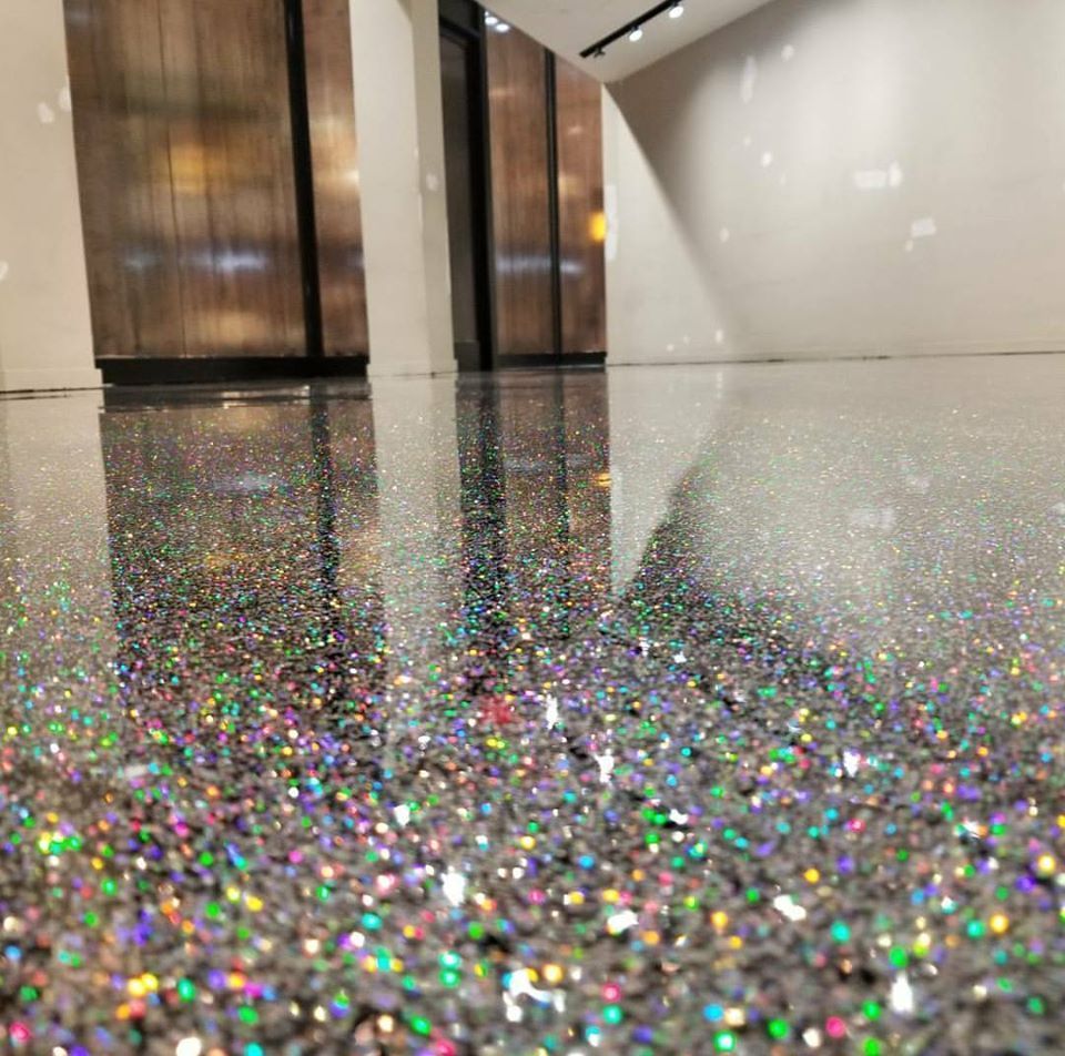 Sparkling glitter-covered floor in a sleek hallway with wood-paneled walls and bright reflections.