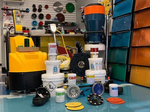 Cleaning supplies and equipment displayed in a store aisle, with mops, buckets, and bottles on shelves