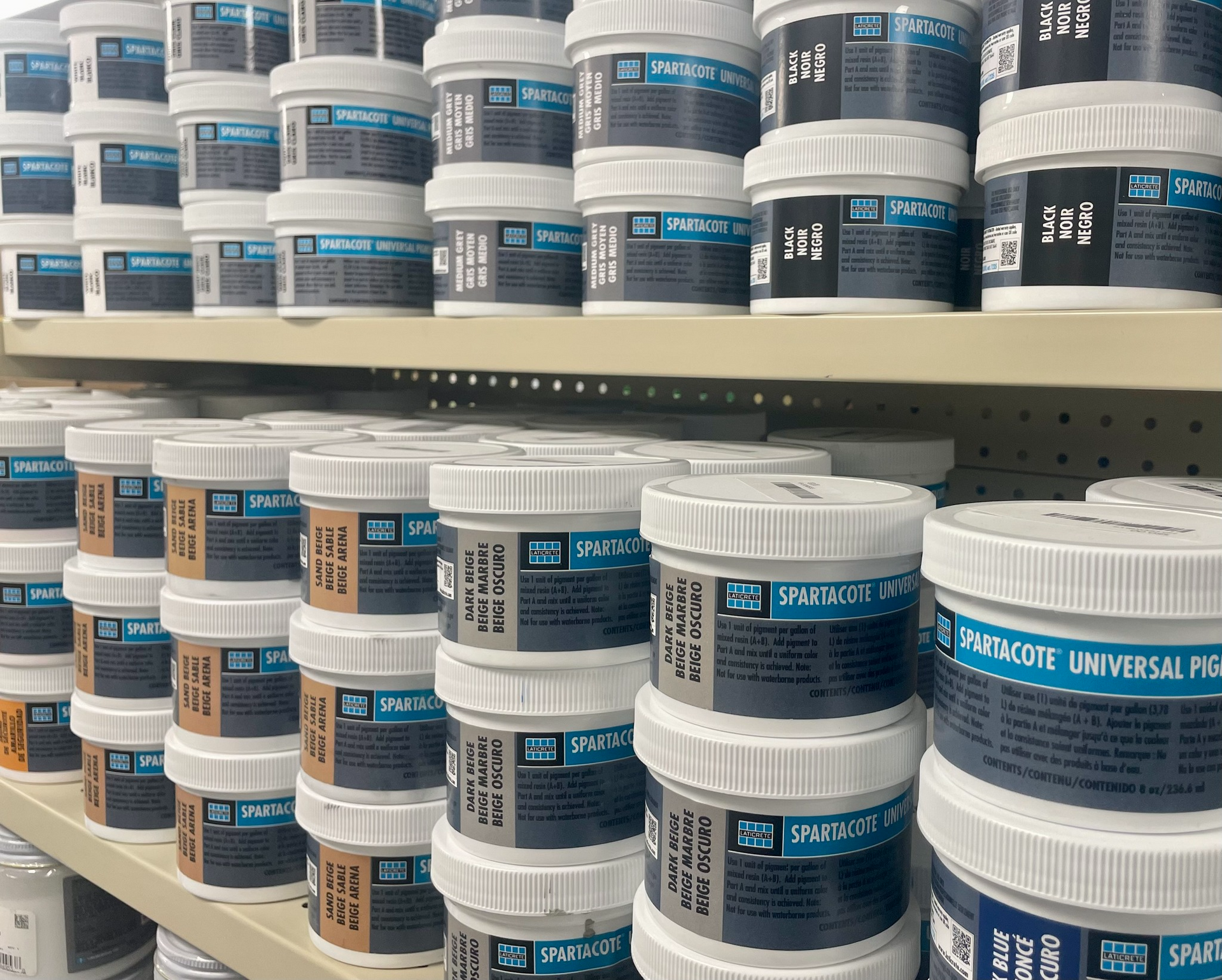 Shelves stocked with stacked white and blue paint cans in a hardware store aisle