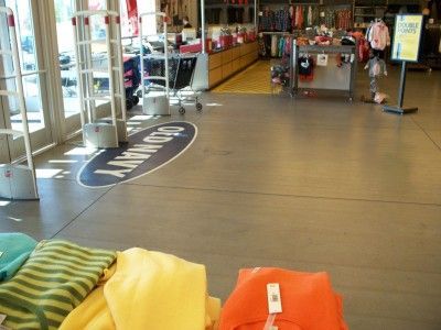 Store entrance with shopping carts, clothing racks, and colorful folded clothes in the foreground