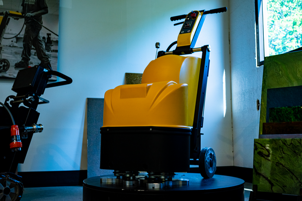 Yellow industrial machine on a pedestal in a dimly lit room, with cables and equipment nearby