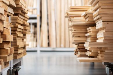 Two carts filled with stacked lumber in a warehouse aisle. Two carts filled with stacked lumber in a warehouse aisle.