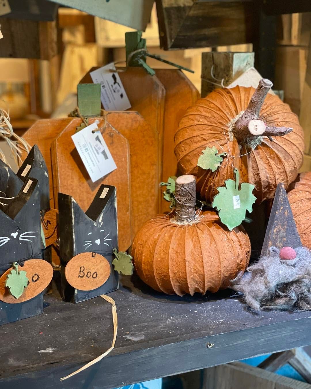 Halloween display of orange pumpkins and decorated black jars on a shelf