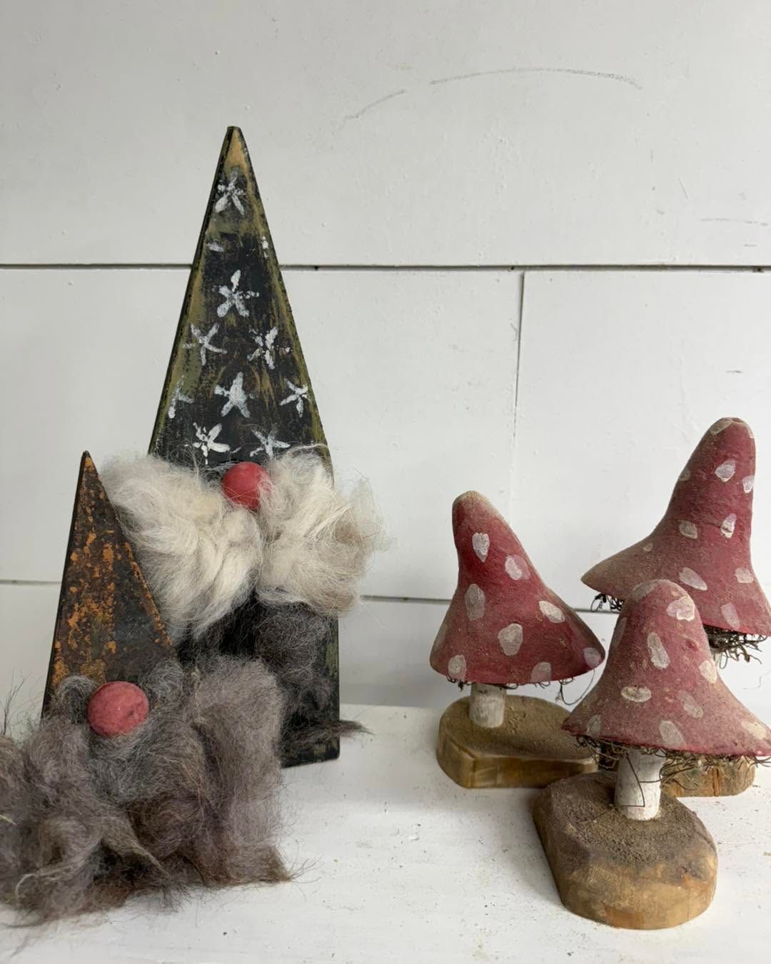 Small handcrafted mushroom and gnome-style figurines on a white surface, including a tall starry triangle decoration