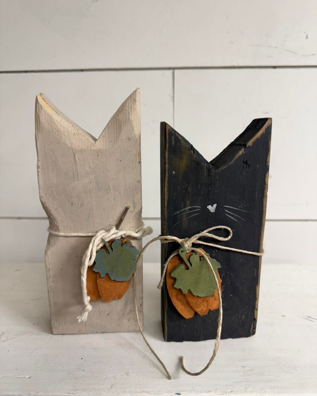 Two rustic wooden cat-shaped planters, one beige and one black, with twine bows and small succulents.