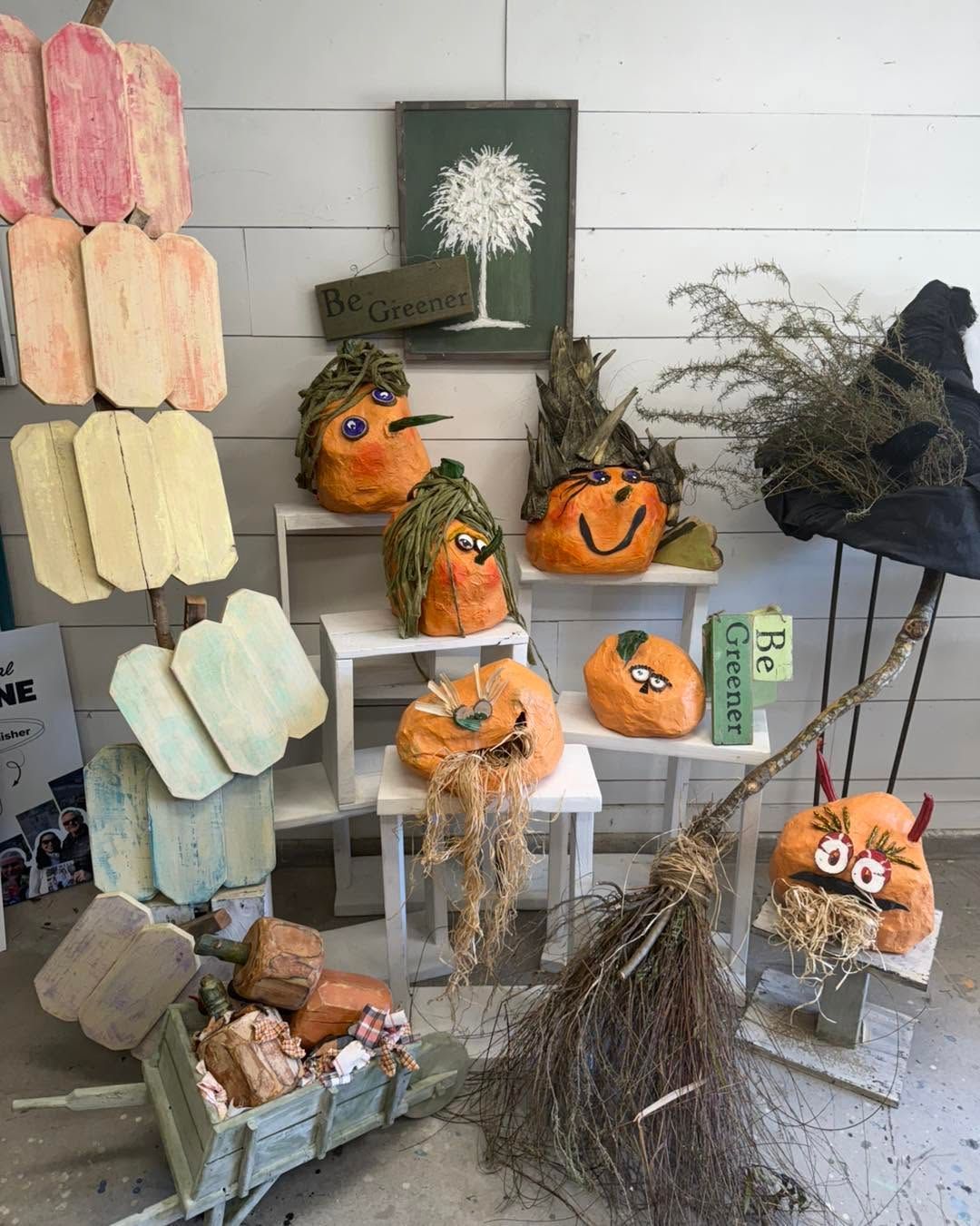 Halloween pumpkin and autumn décor display on shelves with dried branches and neutral-toned wall art