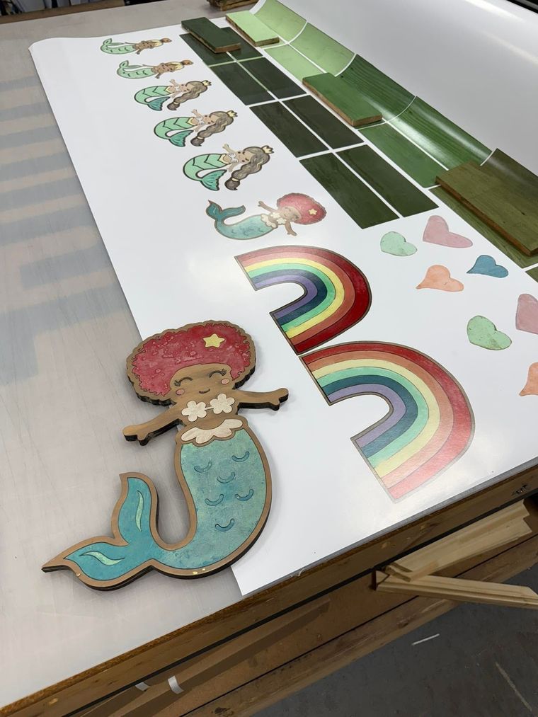 Colorful classroom wall display with rainbow cutouts, hearts, and a mermaid on a whiteboard shelf