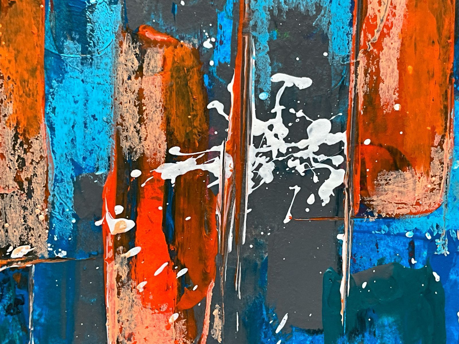 Abstract colorful painting with orange, blue, and gray blocks and white splatters on a textured surface
