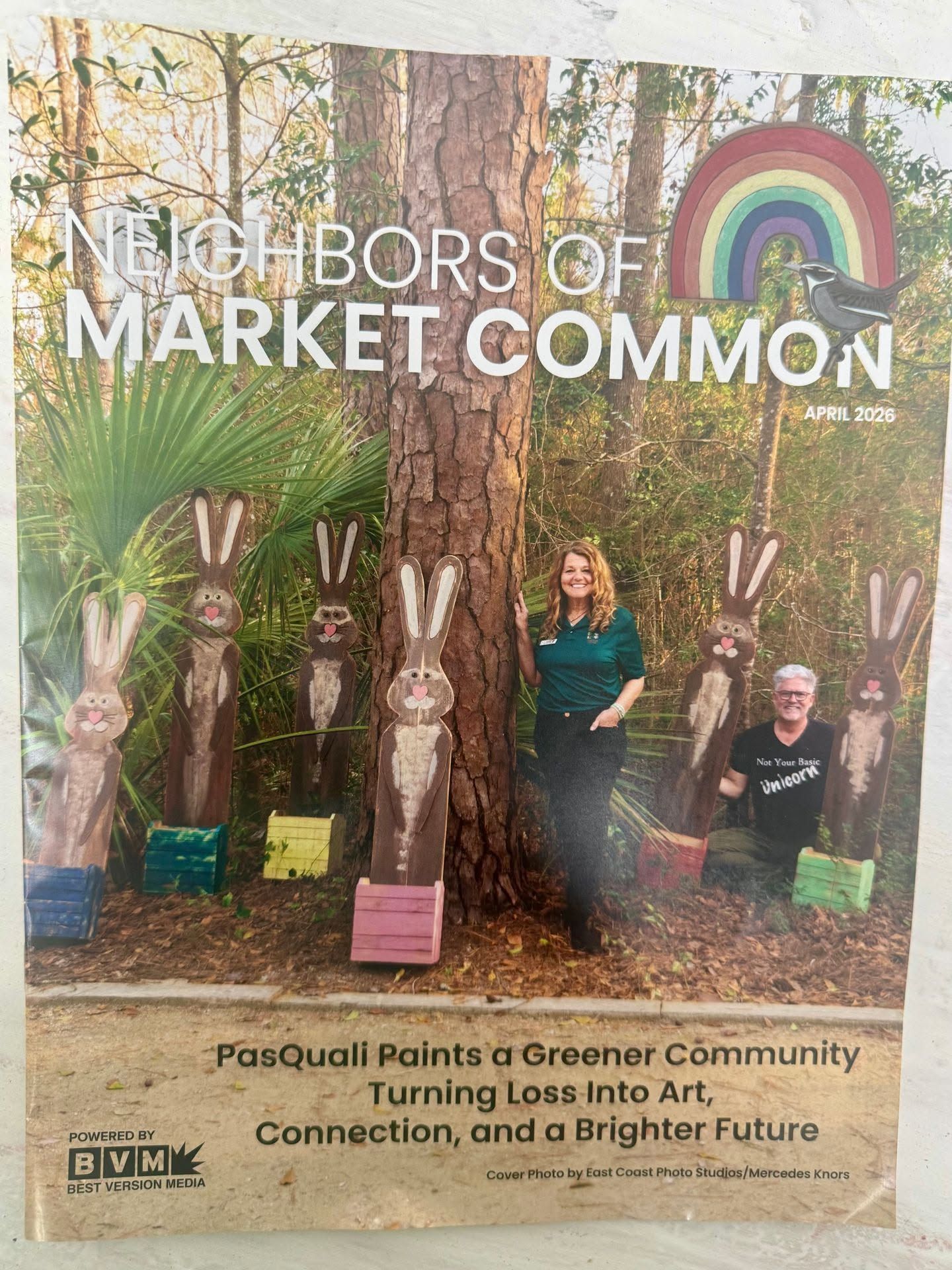 Poster of an art-covered tree mural titled “Neighbors of Market Common” with people seated in a garden setting.