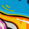 Abstract colorful graffiti with blue, yellow, orange, black, and pink curved lines on a textured wall