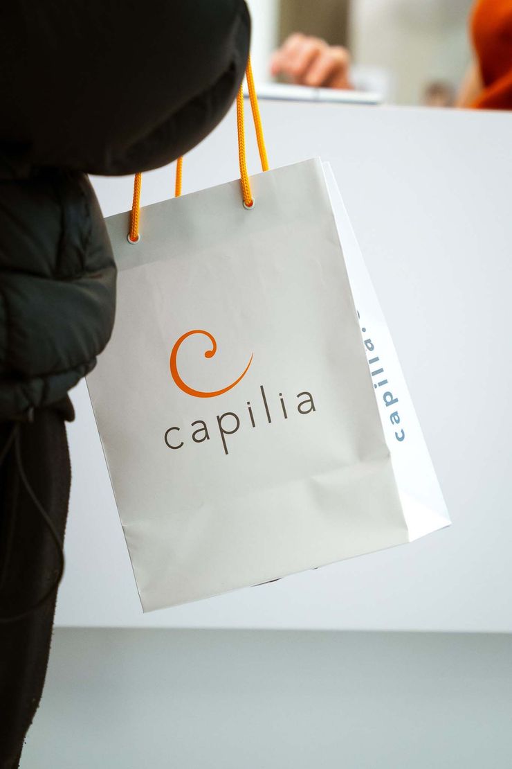 Person holding a white shopping bag with the 