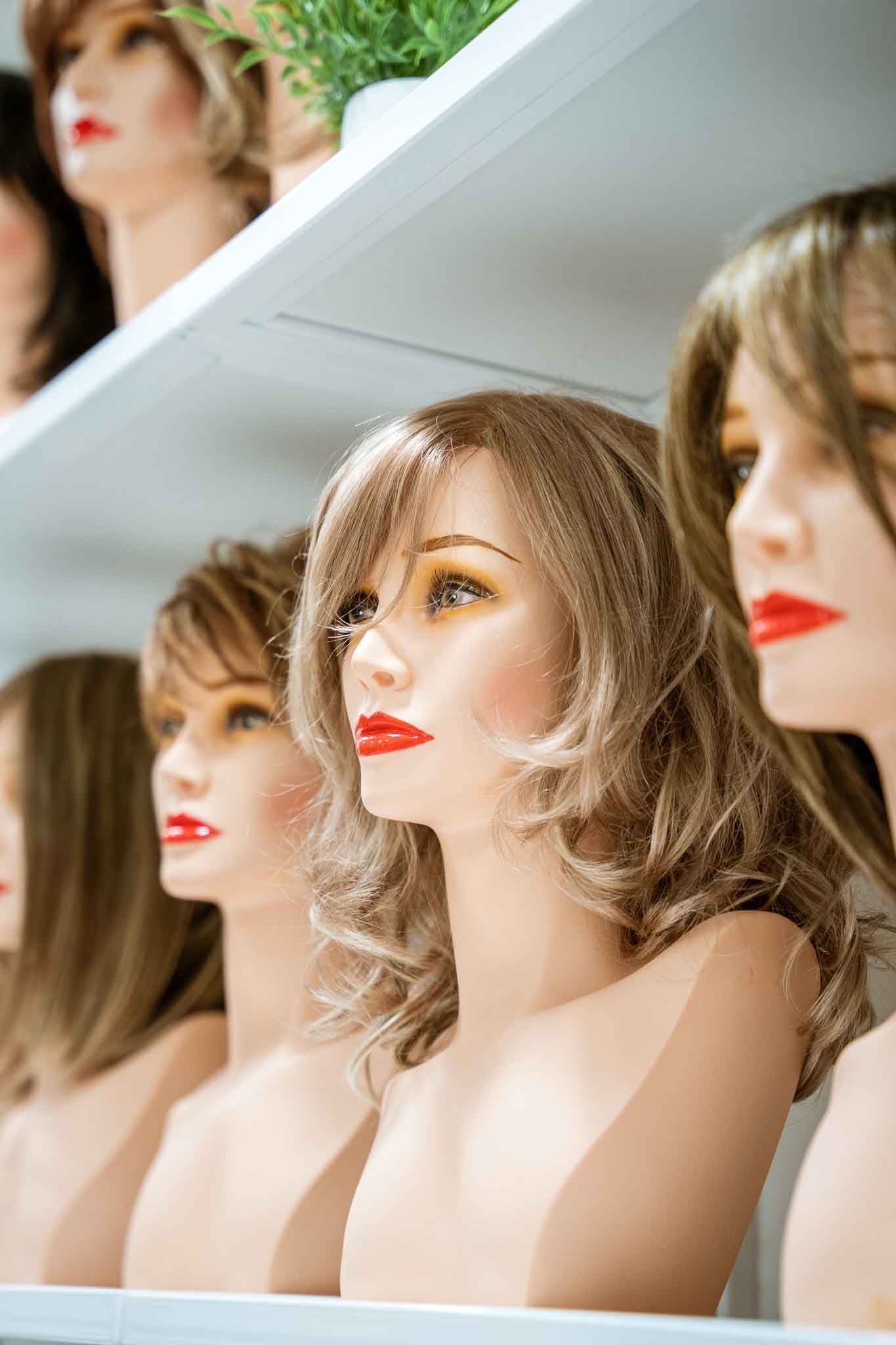 Mannequin heads with wigs on a shelf.
