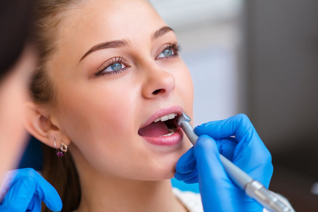 Close-up of a blue-tinted dental mirror and tools on a white surface