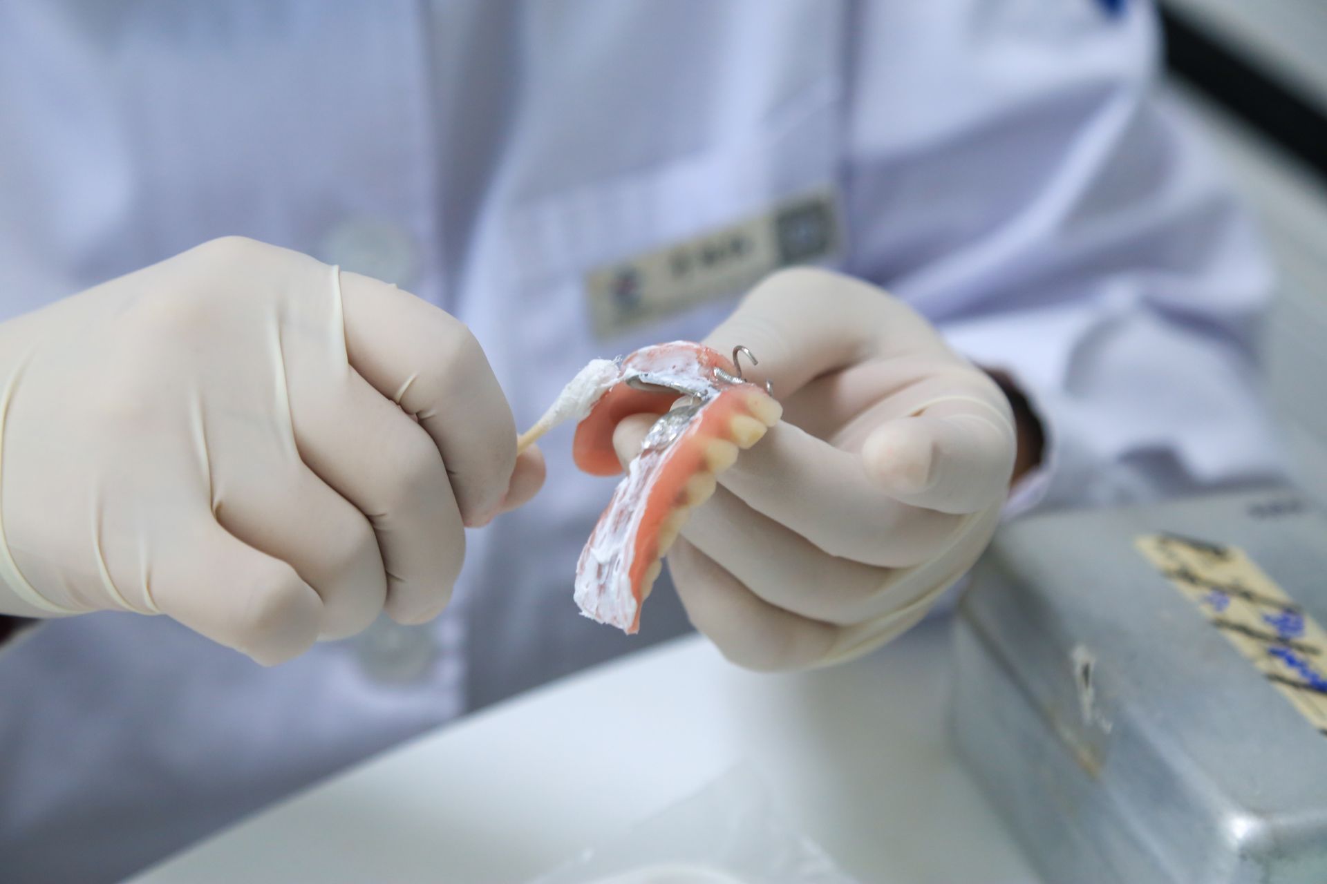 Gloved hands holding a dental mold with orange and white material in a clinical setting