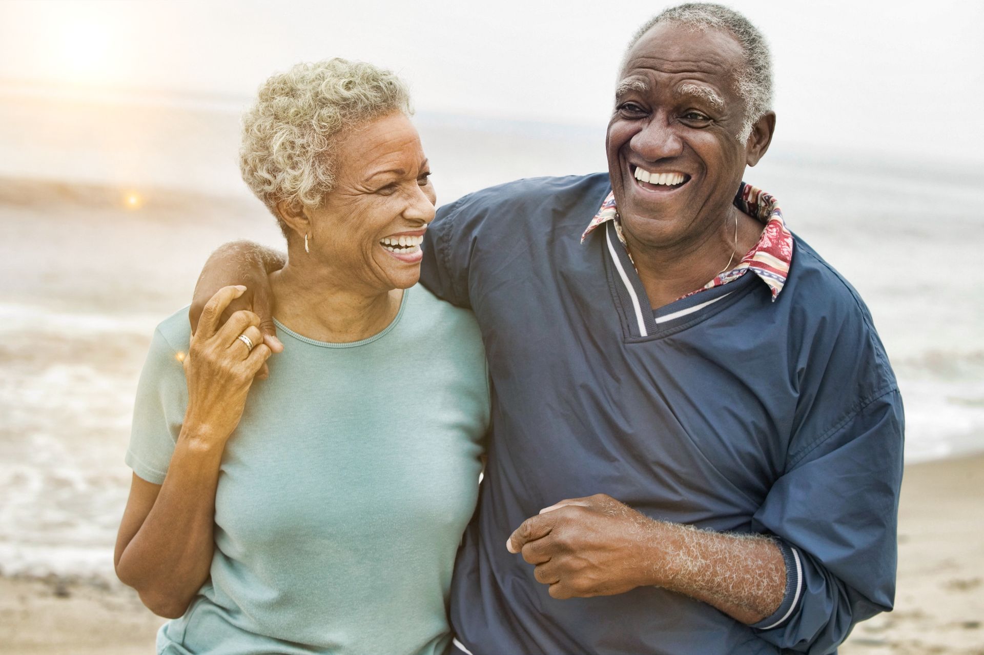 Smiling couple walking arm in arm on a beach at sunset